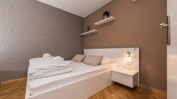 A modern bedroom with a bed, bedside table, and wall-mounted shelves.