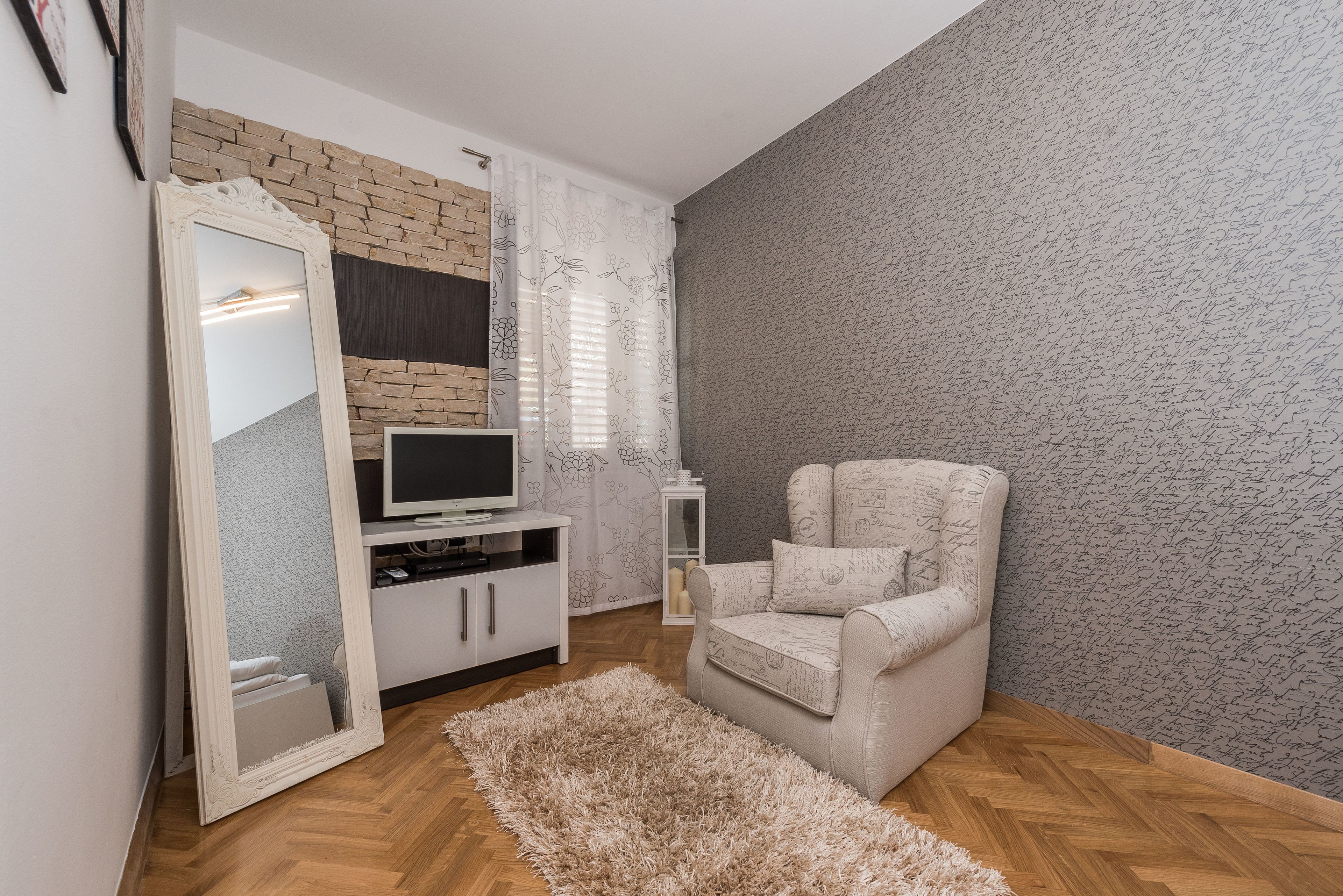 Una sala de estar con sofá, televisión, espejo y pared con diseño.