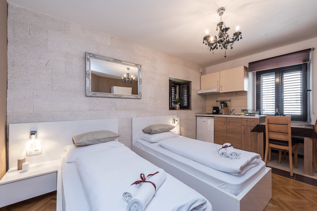 Ein Hotelzimmer mit zwei Betten, einer Küchenzeile, einem Essbereich und einem Badezimmer.