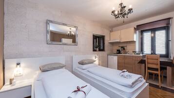A hotel room with two beds, a kitchenette, a dining area, and a bathroom.
