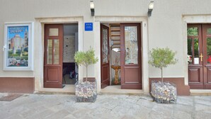 A building entrance with two doors, a sign indicating "2", and two potted trees. - Apartments Donat Zadar (Zadar)
