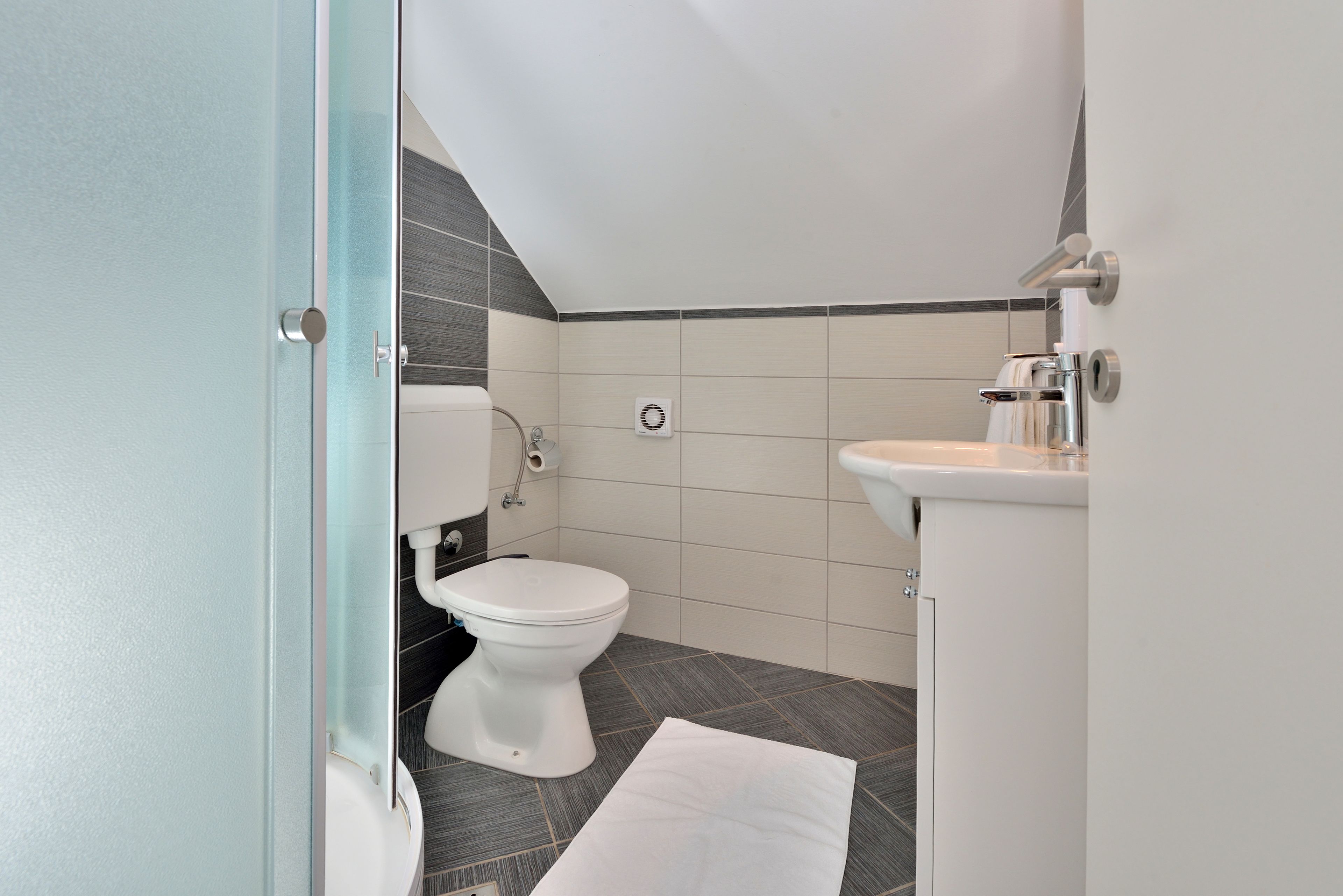 Un baño moderno con inodoro, lavamanos y ducha.