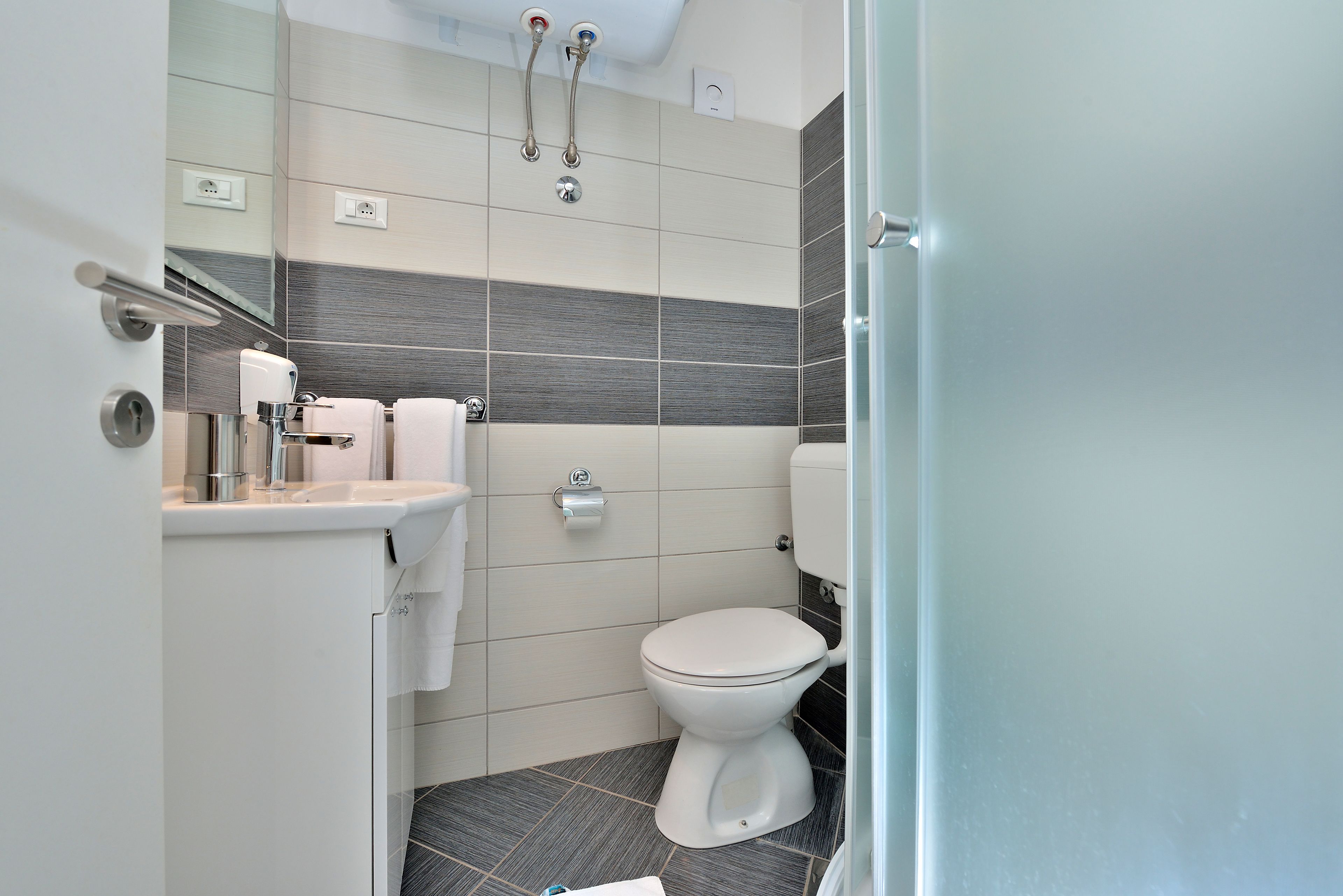 A modern bathroom with a toilet, sink, and shower.