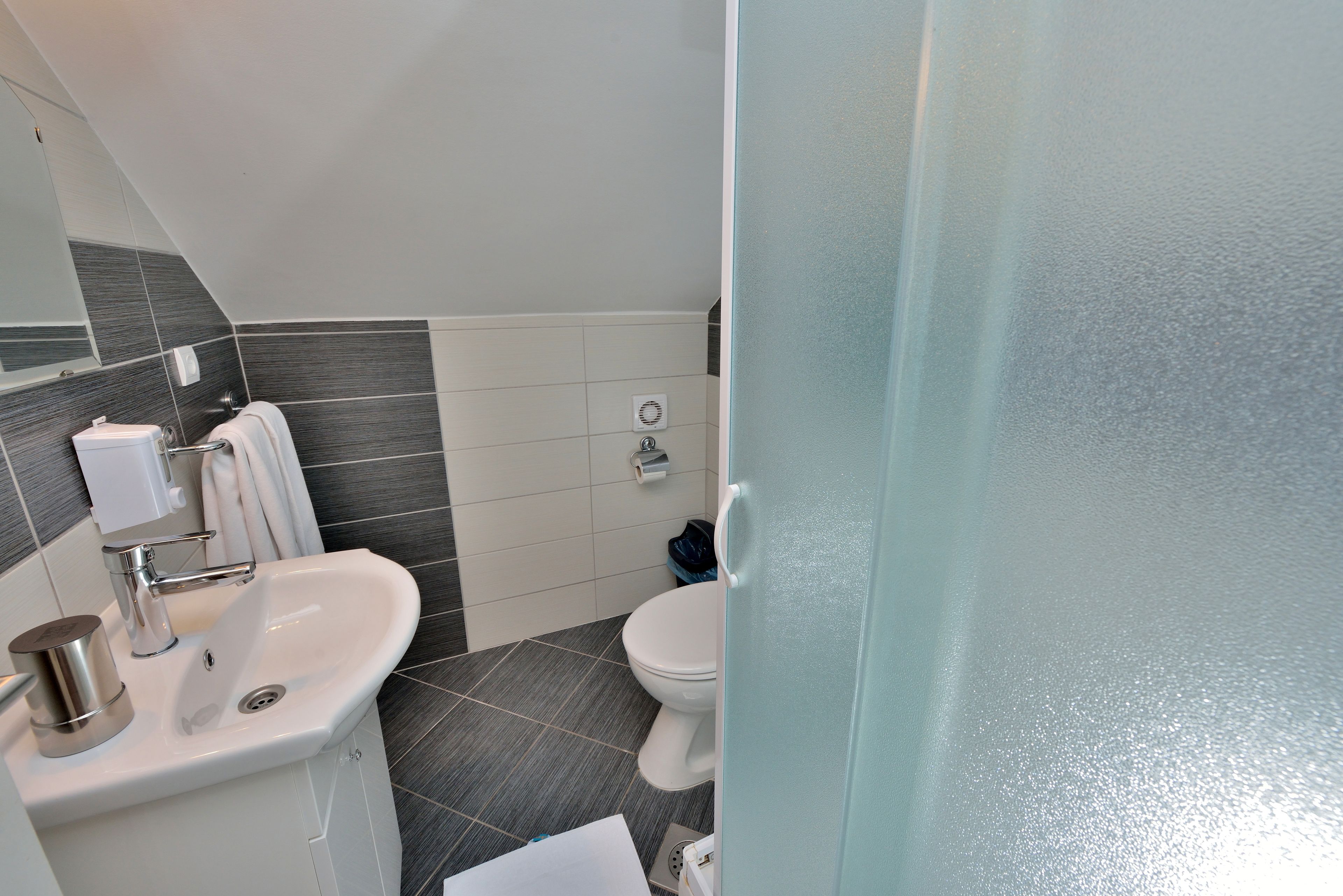 Un baño moderno con lavamanos, espejo, inodoro y toallero.