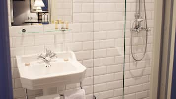 A bathroom with a white sink, a glass shower enclosure, and a checkered floor.