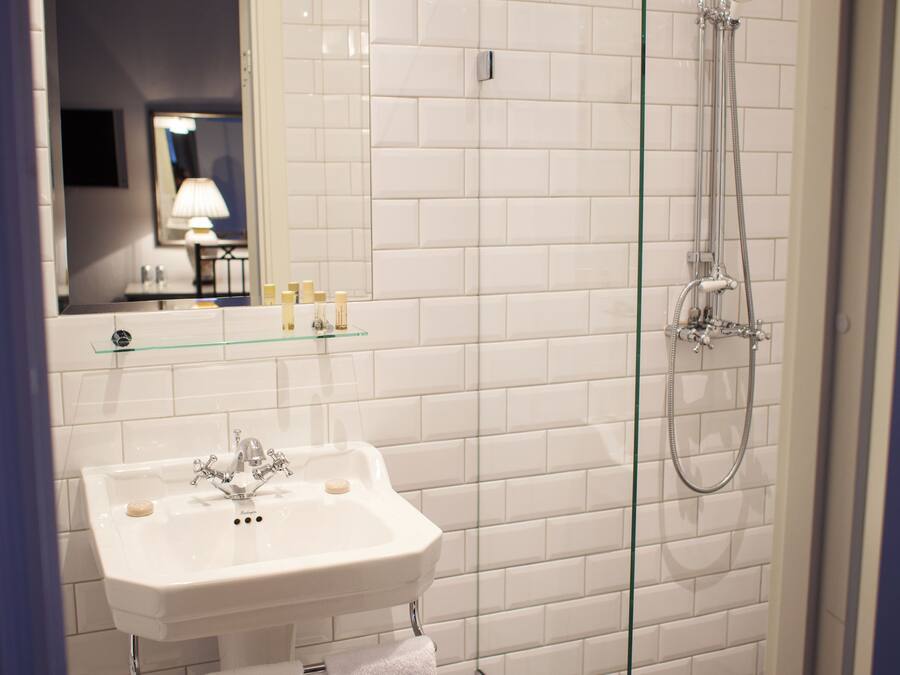 A bathroom with a white sink, a glass shower enclosure, and a checkered floor.