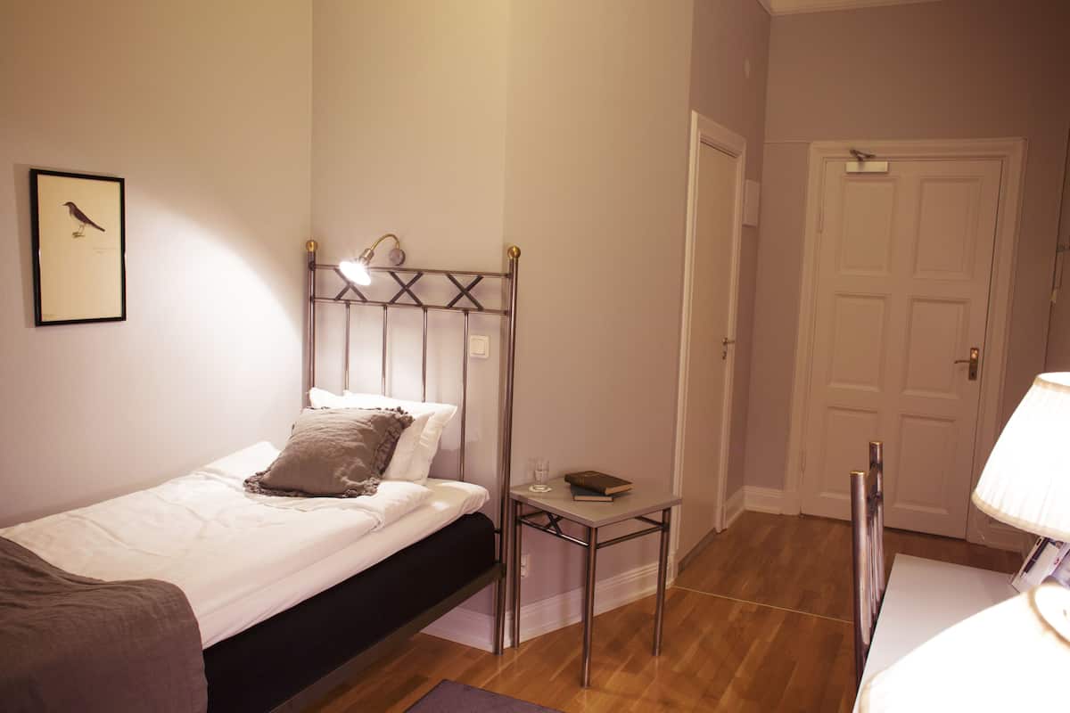 Ein Schlafzimmer mit Bett, Nachttisch, Lampe und einem gerahmten Bild an der Wand.