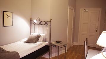 A bedroom with a bed, bedside table, lamp, and a framed picture on the wall.