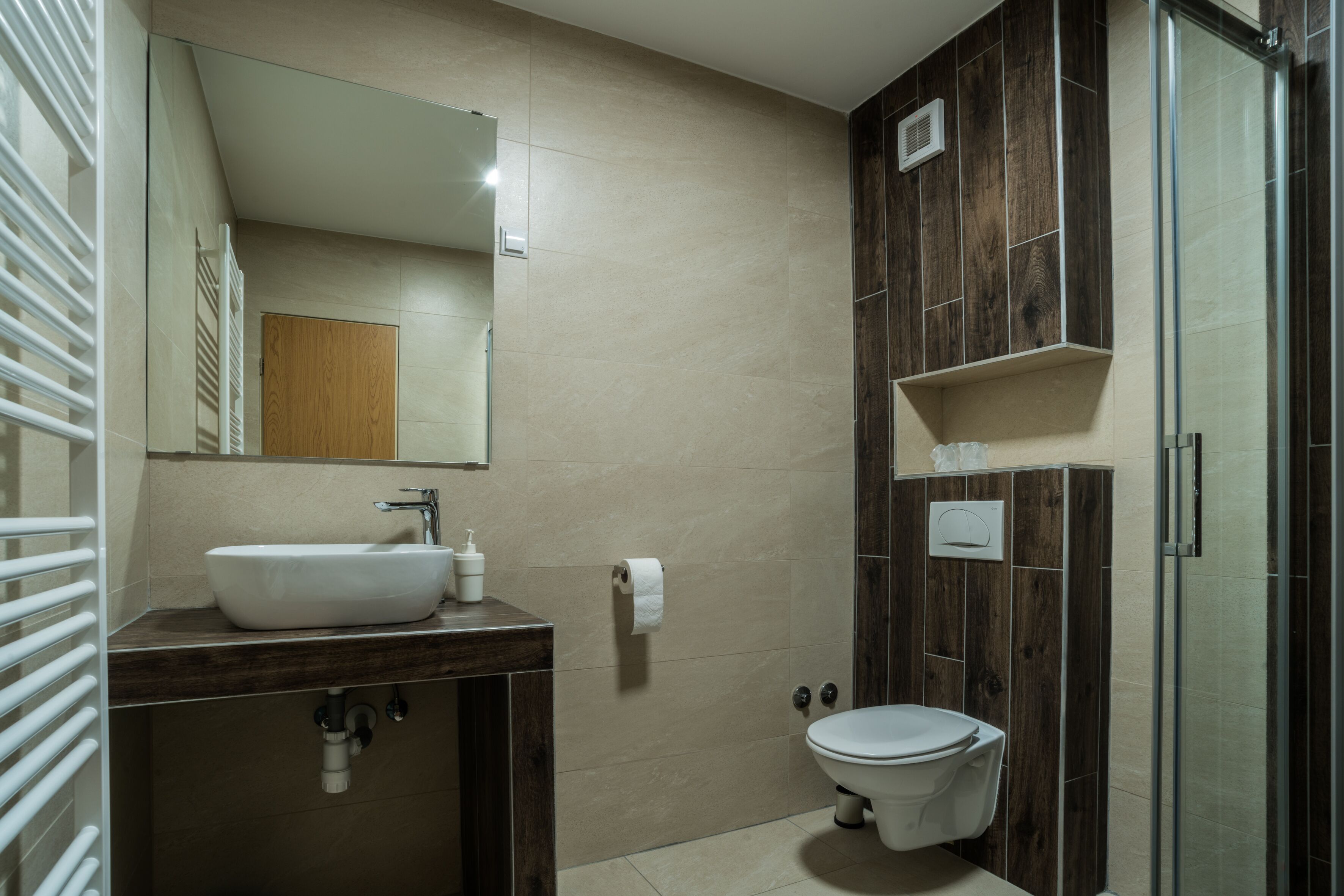 Une salle de bain moderne avec un meuble-lavabo en bois, un évier, des toilettes et une douche à parois de verre.