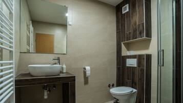 Une salle de bain moderne avec un meuble-lavabo en bois, un évier, des toilettes et une douche à parois de verre.