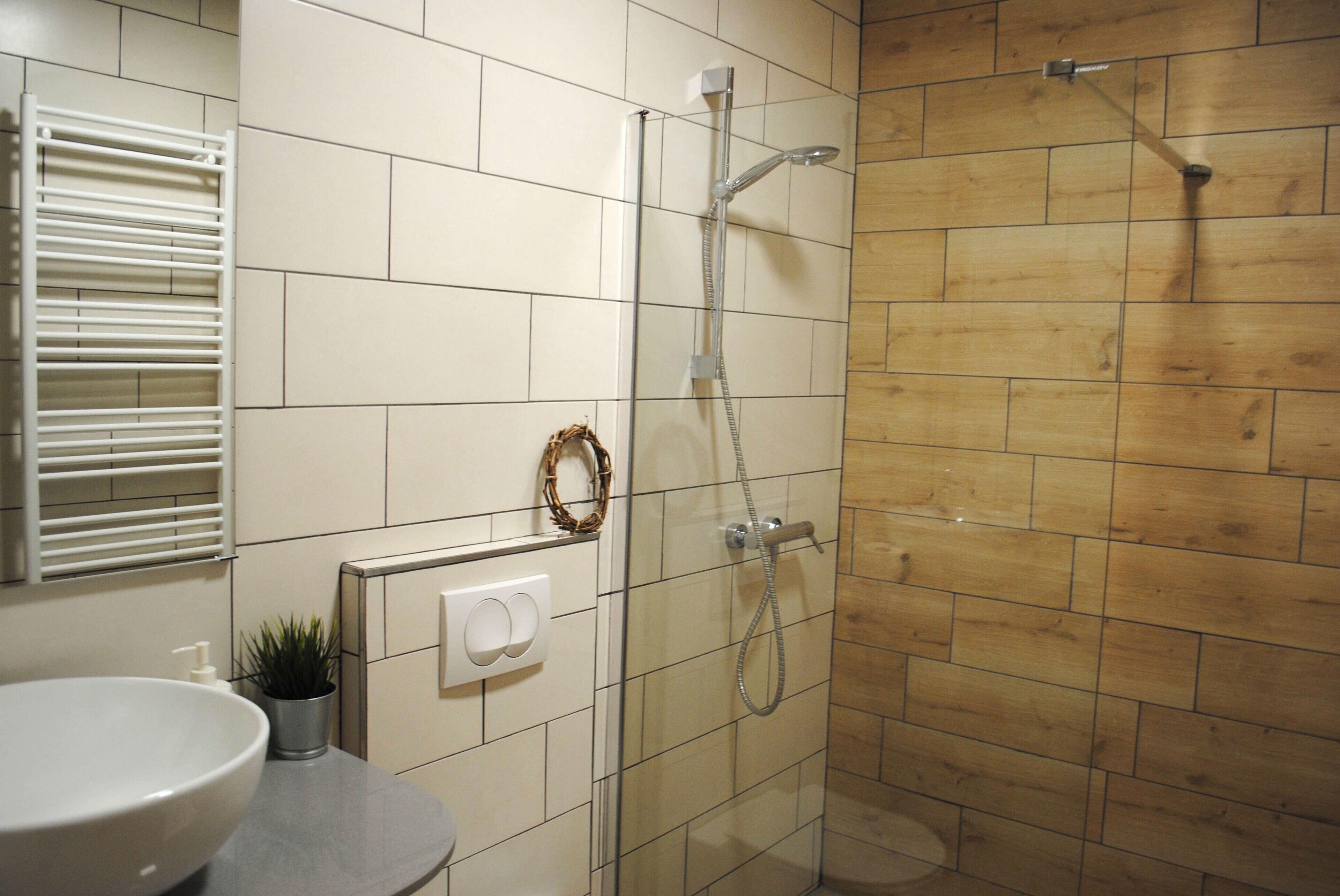 Un bagno con doccia, lavandino e porta asciugamani.