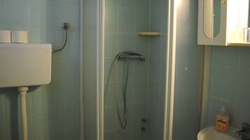 Een badkamer met douche, toilet en wastafel.