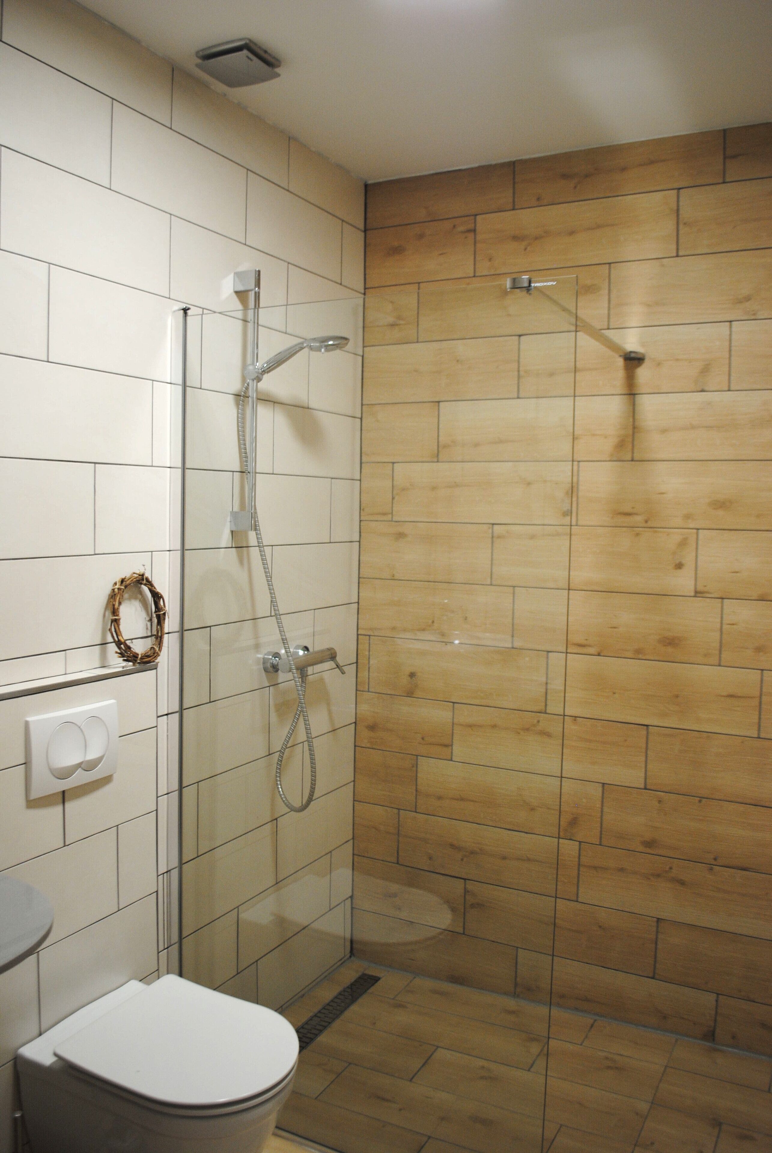 A bathroom with a glass-enclosed shower, a white toilet, and a wooden wall.