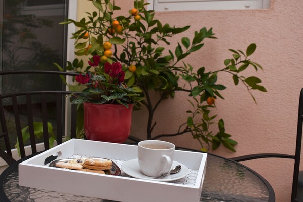A table with a tray containing a cup of coffee, a plate with cookies, and a potted plant with green leaves and orange fruits.
