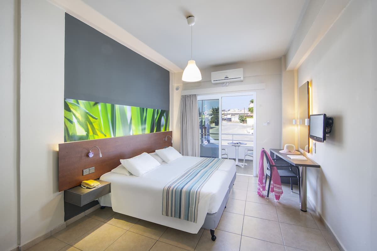 A modern hotel room with a large bed, a desk, and a TV.