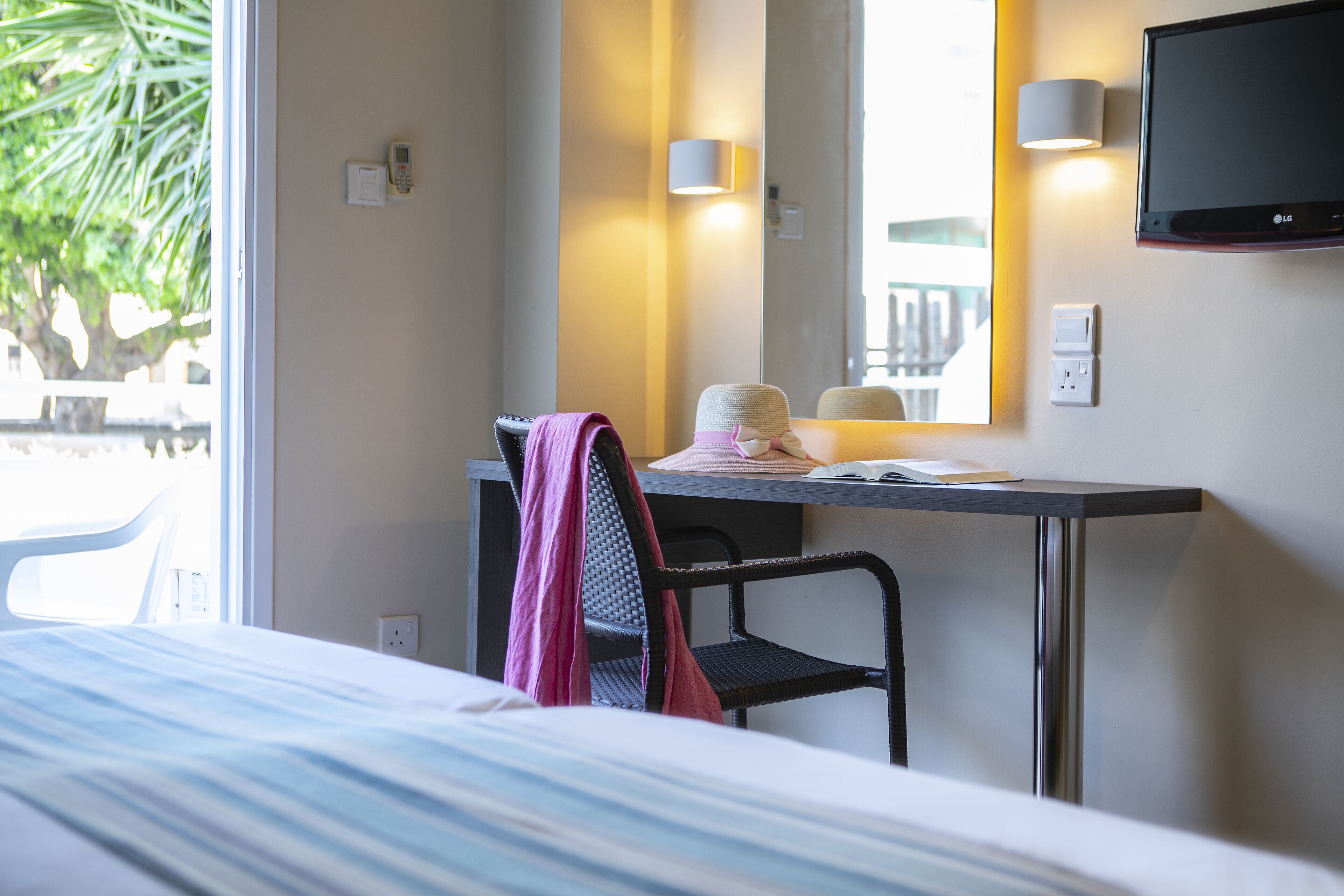 Una camera d'albergo con un letto, una scrivania con una sedia, uno specchio e una televisione.
