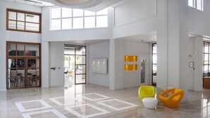 A spacious lobby with a high ceiling, large windows, and a modern design. - Mayfair Gardens (Paphos)