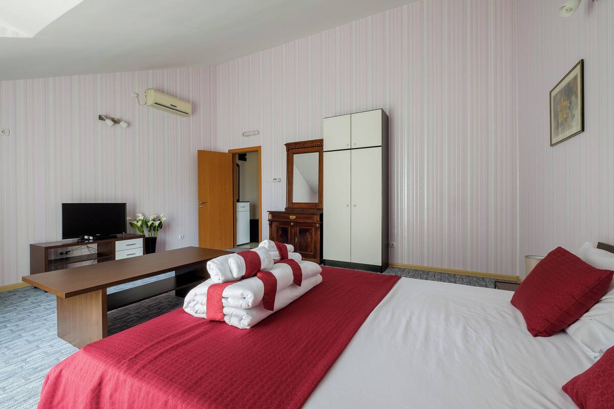 Une chambre d’hôtel comprenant un lit, un bureau, une télévision, une armoire et un miroir.