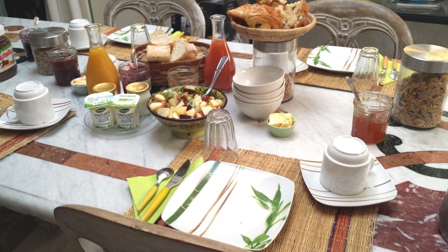 A breakfast table set with various food items, including bread, fruit, and condiments.