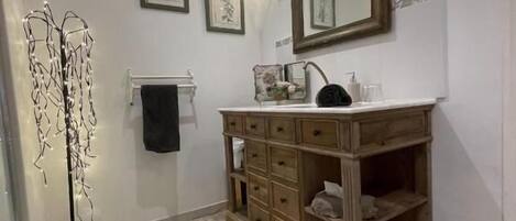Un baño con tocador de madera, un espejo grande, luces de pared y una lámpara de pie.