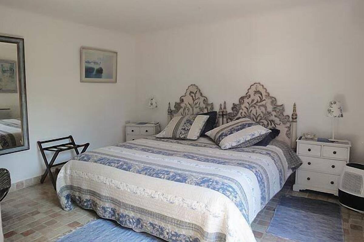 A bedroom with a bed, nightstands, a chair, and a small table.