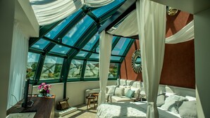 Un dormitorio con un tragaluz grande, una cama, un escritorio con ordenador y una ventana con cortinas.