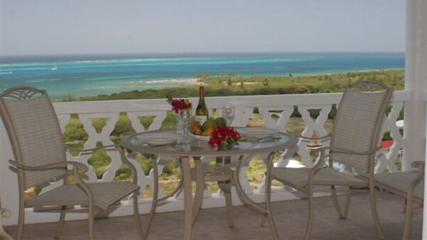 Una mesa para dos con sillas en un balcón con vista al mar.