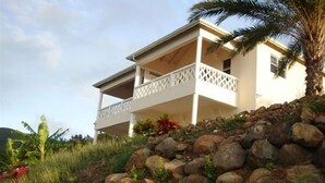 A two-story house with a balcony, surrounded by a rocky landscape and some vegetation. - South Coast Ocean View Apartments (Cades Bay)