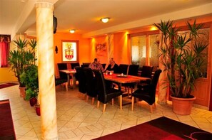 A dining area with a marble column, potted plants, and a large painting on the wall. - Hotel Garni Zerza (Hermagor-Pressegger See)