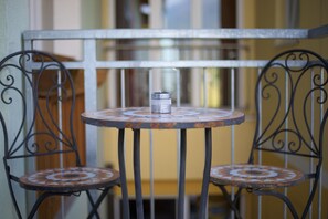 A small round table with a candle, two metal chairs with patterned seats, and a metal railing in the background. - Hotel Garni Zerza (Hermagor-Pressegger See)