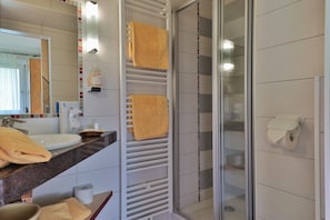 A modern bathroom with a sink, mirror, towel rack, and glass shower enclosure. - Hotel Garni Zerza (Hermagor-Pressegger See)