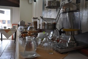 Un espace dédié au café, équipé d’une machine à café, de carafes en verre et d’une variété de tasses et de verres à café.