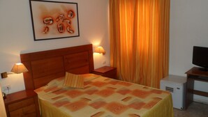 Une chambre d’hôtel avec un lit, une télévision, un bureau et une lampe.