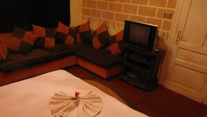 A hotel room with a bed, a sofa, a television, and a fireplace. - City Plaza Hostel (Cairo)