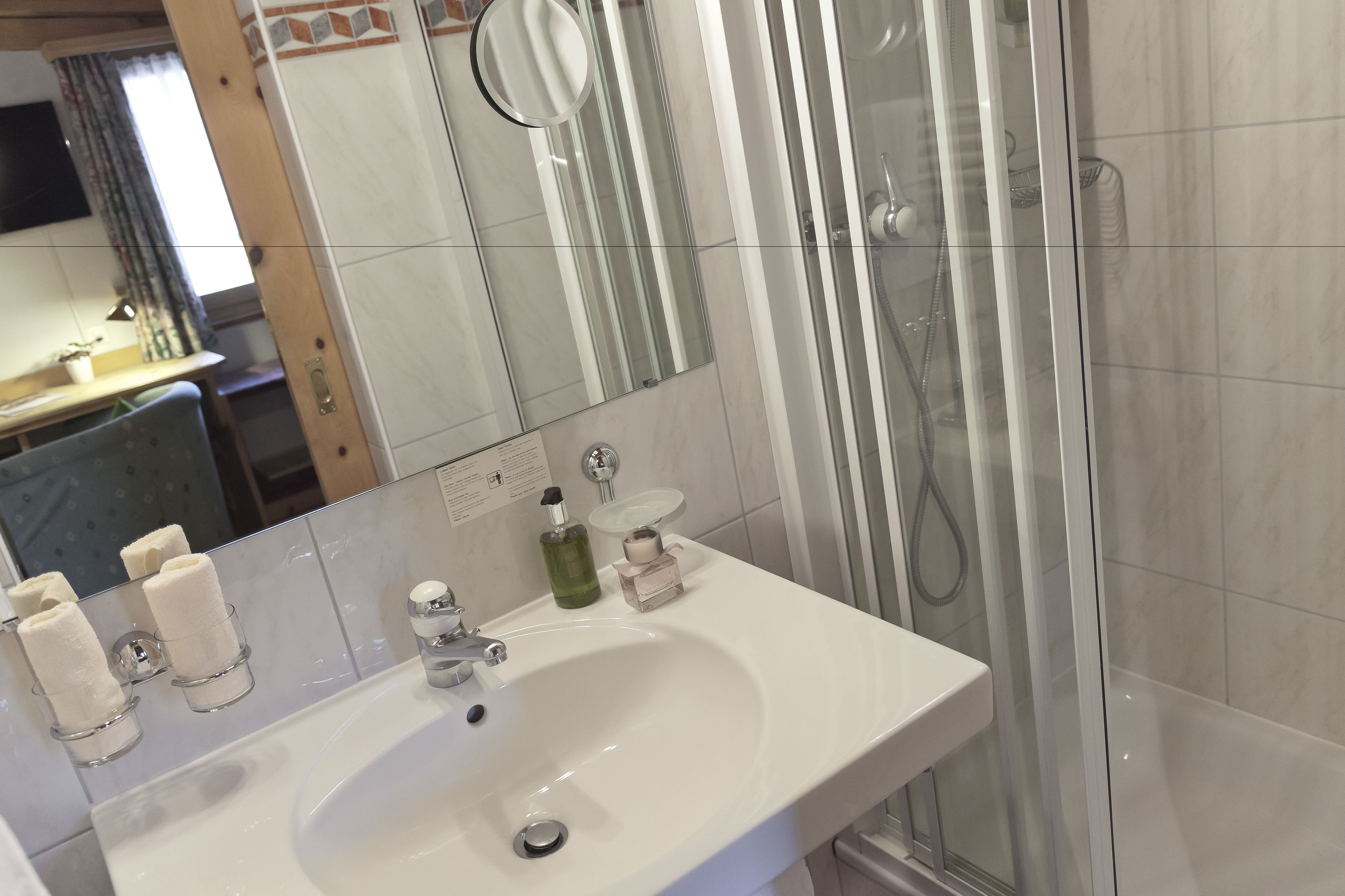 Une salle de bain avec un lavabo blanc, un miroir et un espace douche.