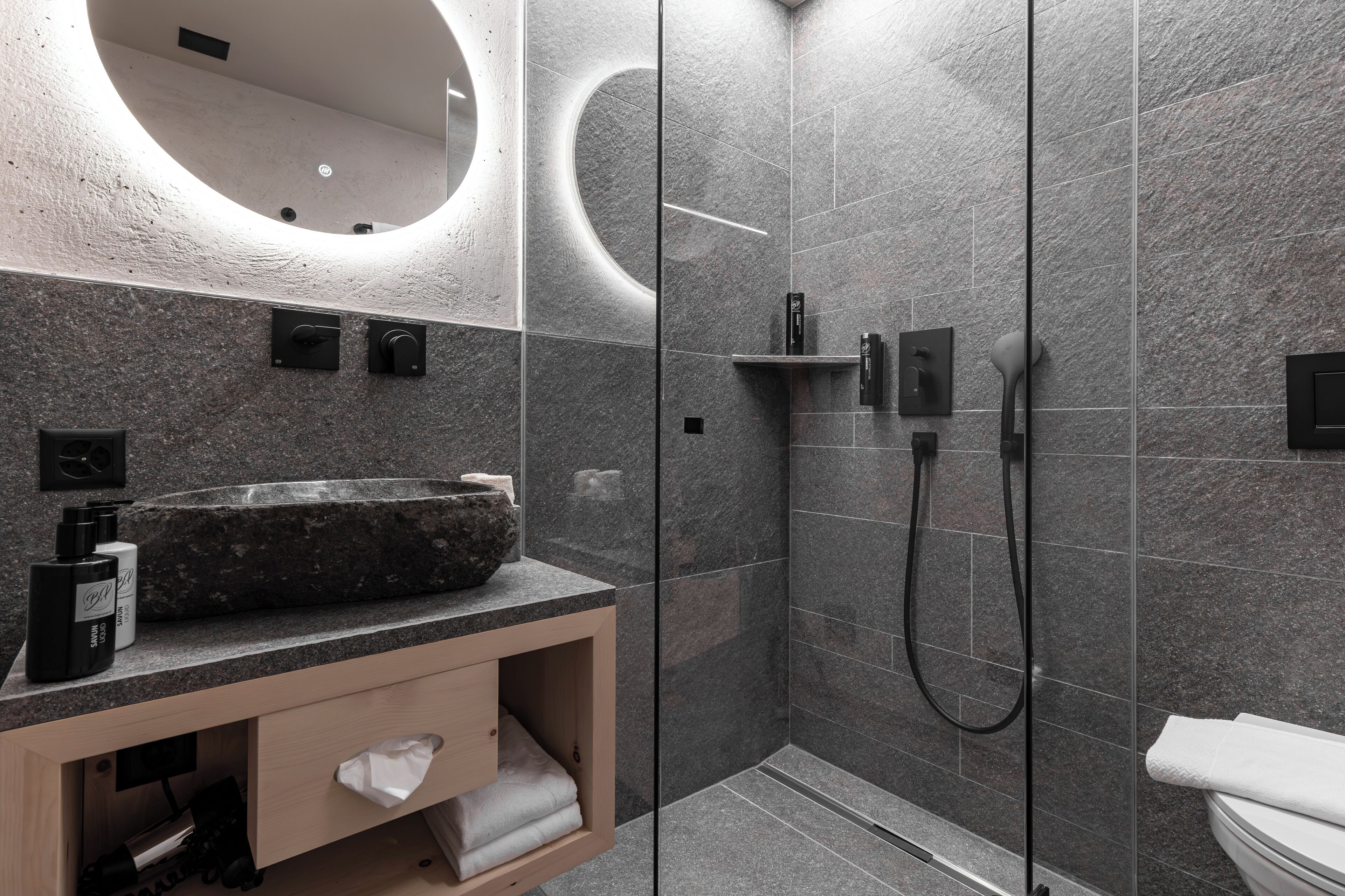 Une salle de bain moderne dotée d’un grand lavabo, d’une douche à parois de verre et de toilettes.