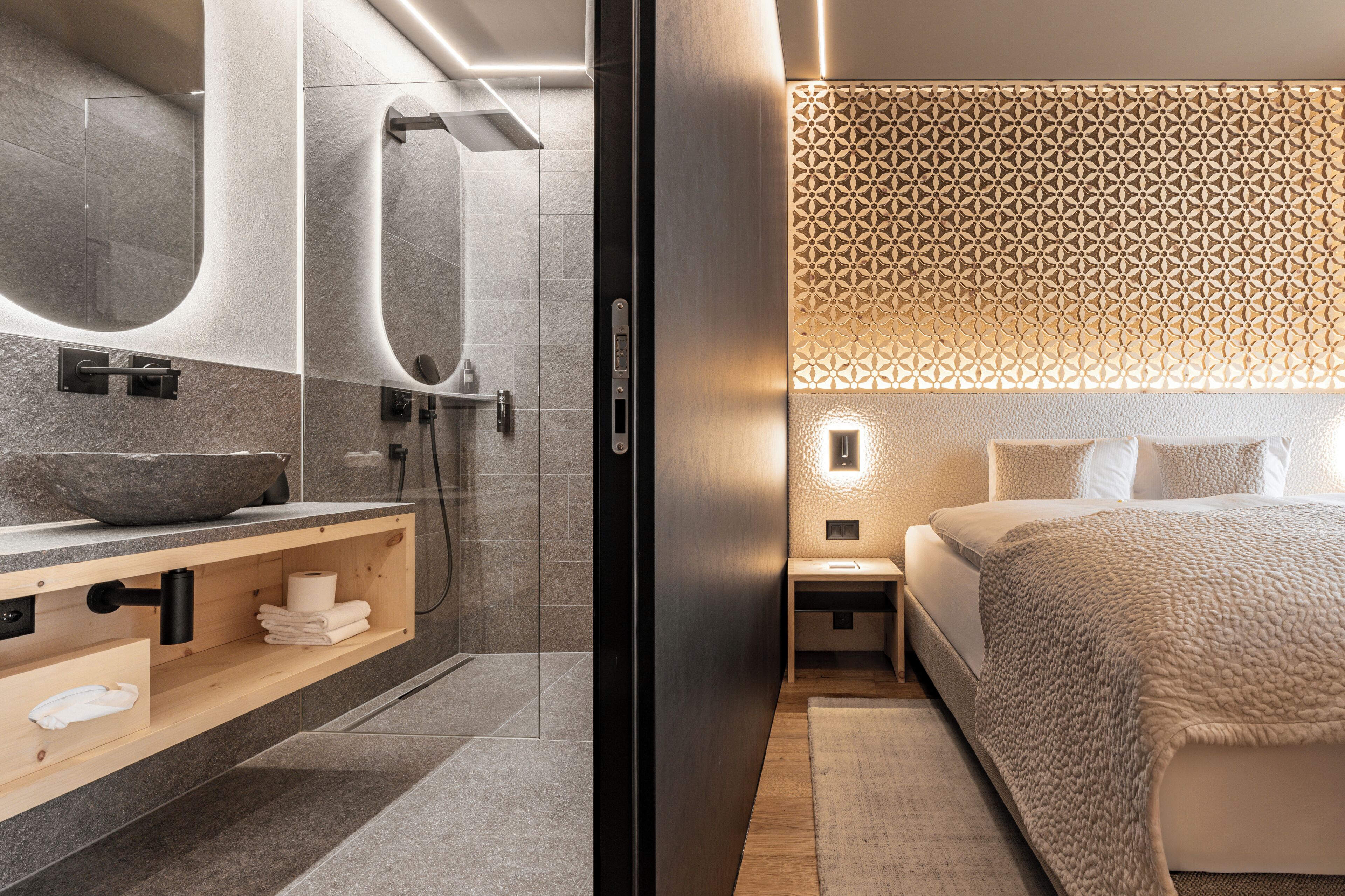 A modern bathroom with a large mirror, a stone sink, and a shower.