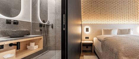A modern bathroom with a large mirror, a stone sink, and a shower.