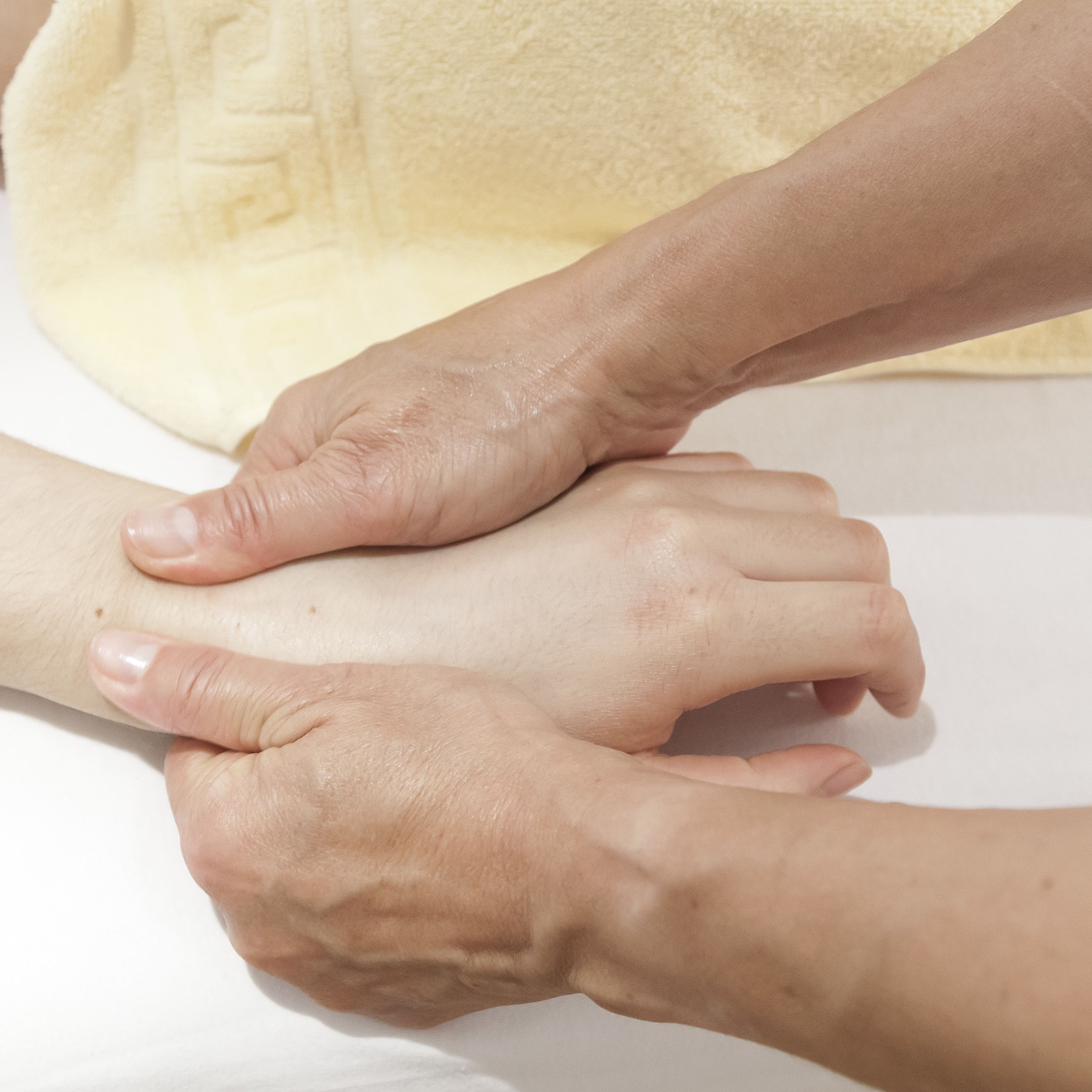 Gros plan sur des mains effectuant un massage sur le bras d’une personne.