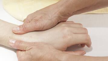 Gros plan sur des mains effectuant un massage sur le bras d’une personne.