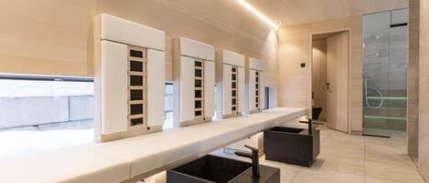 A modern bathroom with a long countertop, multiple sinks, and a glass shower enclosure.