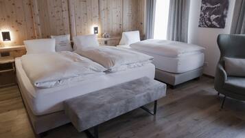 A hotel room with two beds, a bench, a chair, wooden walls, and a painting.