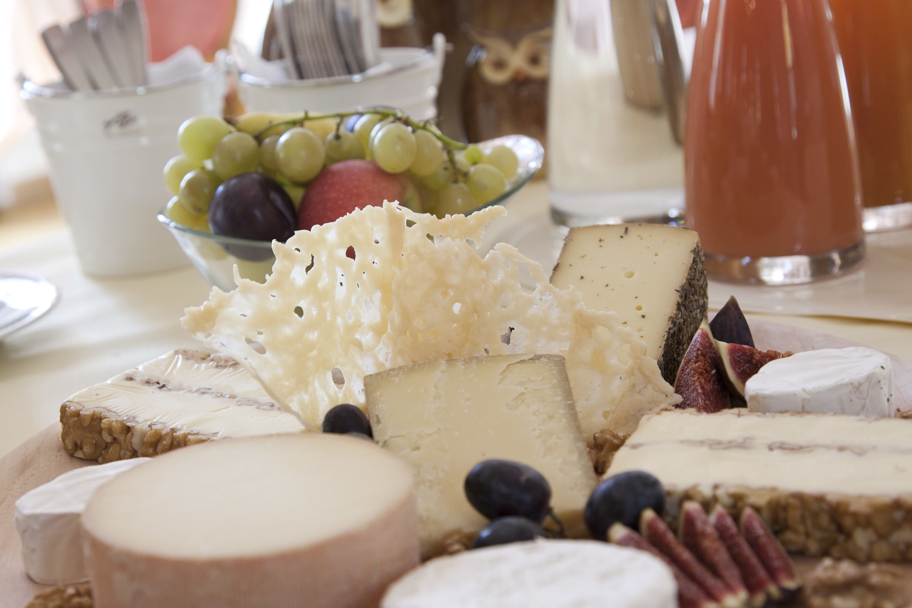 A variety of cheeses and fruits on a table.