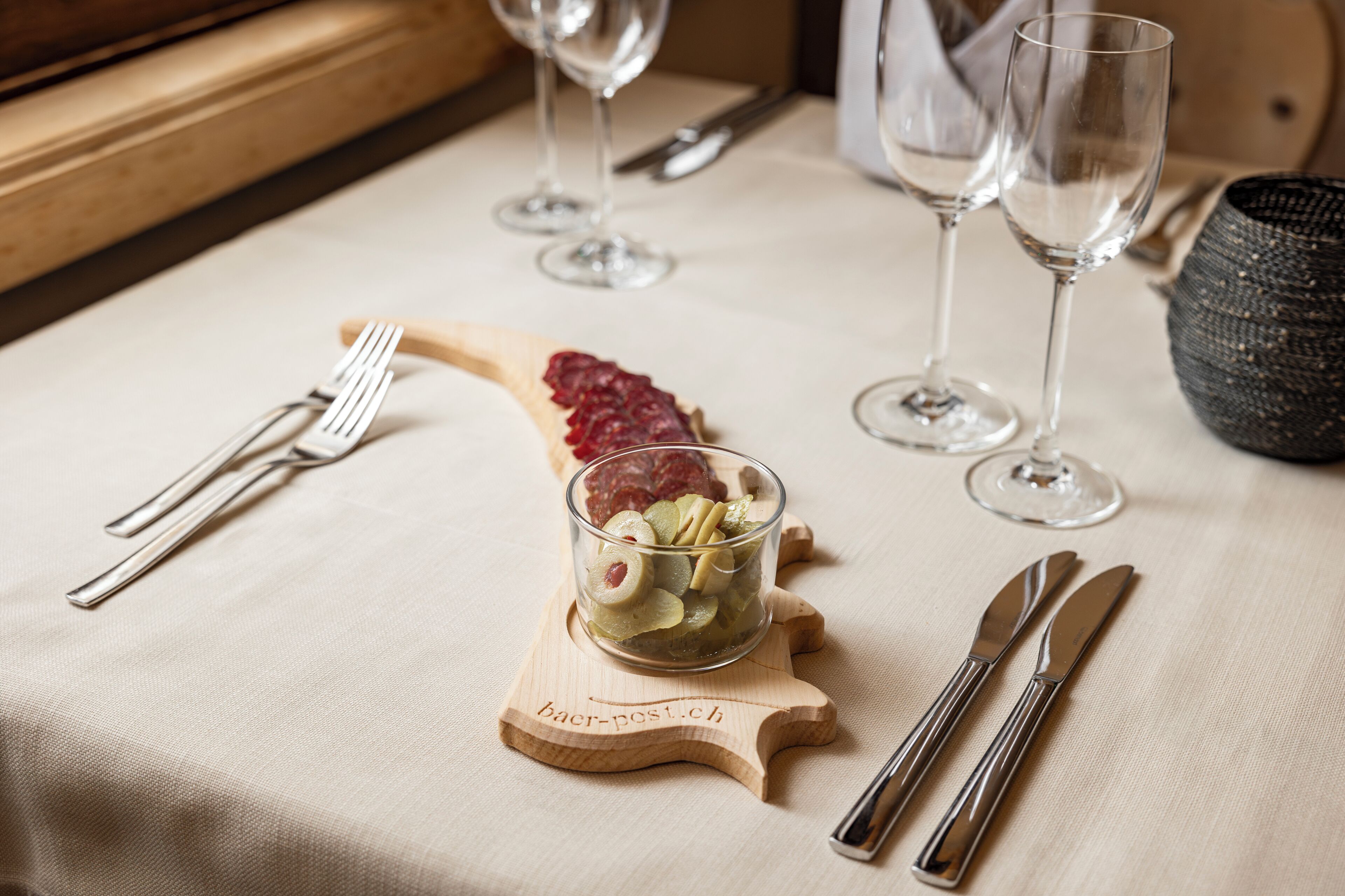 Een eettafel met bestek, een pot jam en wijnglazen.