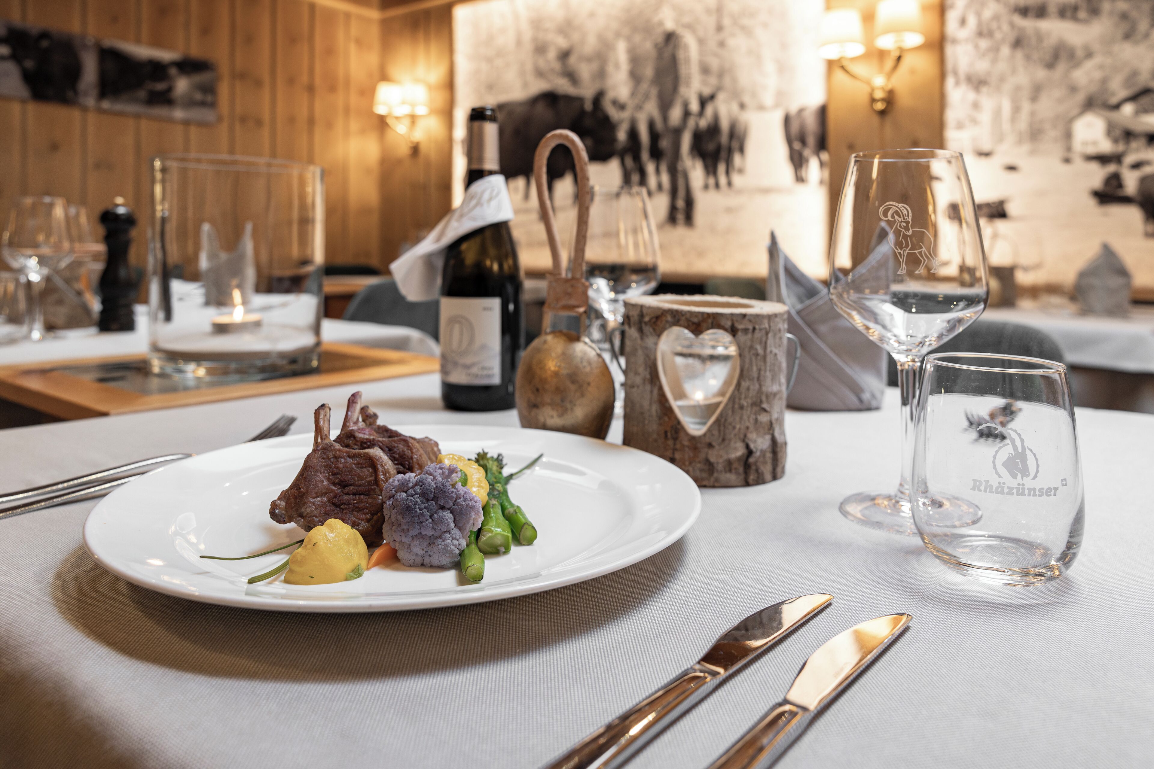 A dining table with a plate of food, wine glasses, and cutlery.