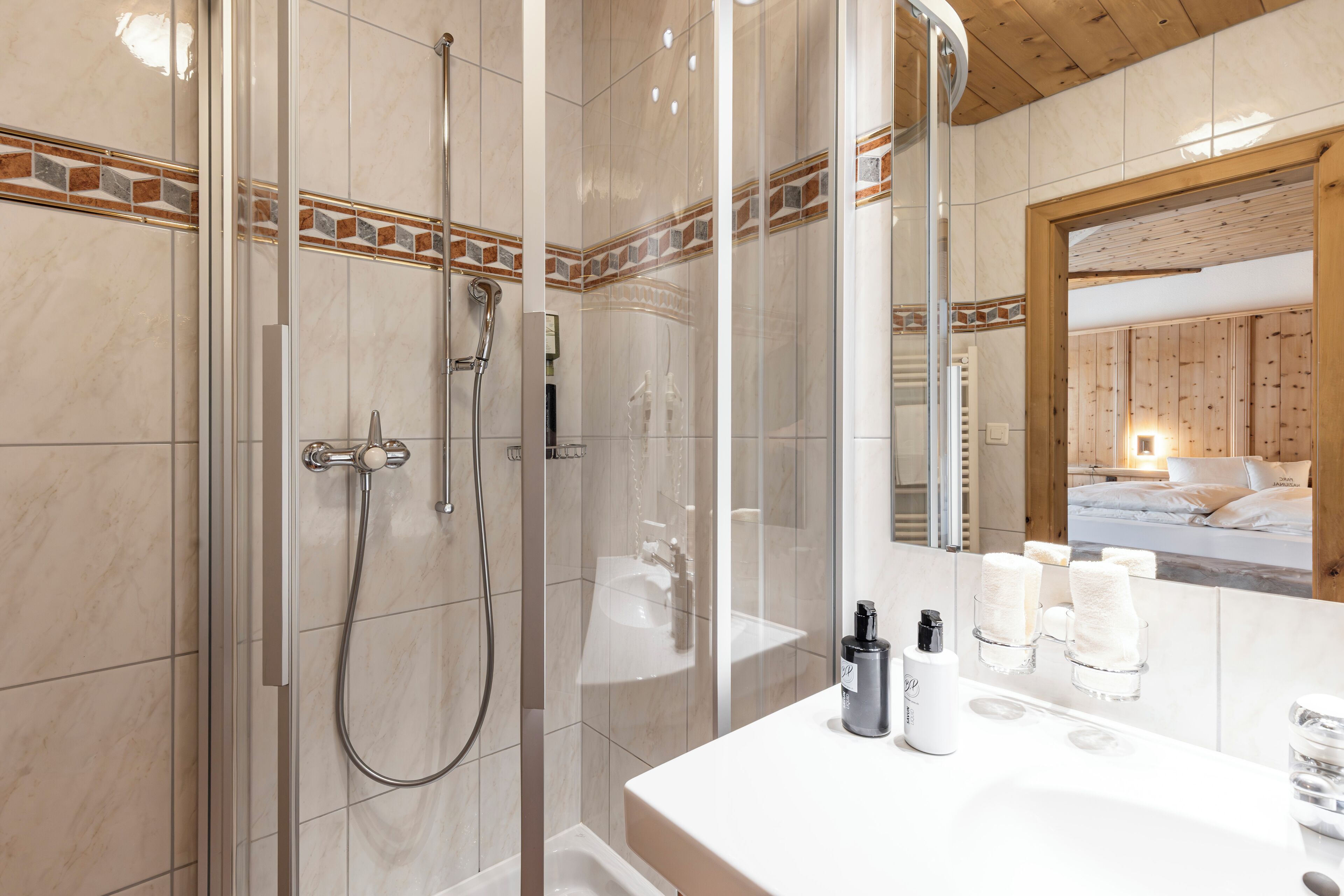 A modern bathroom with a glass-enclosed shower, a white sink with a mirror, and a wooden ceiling.