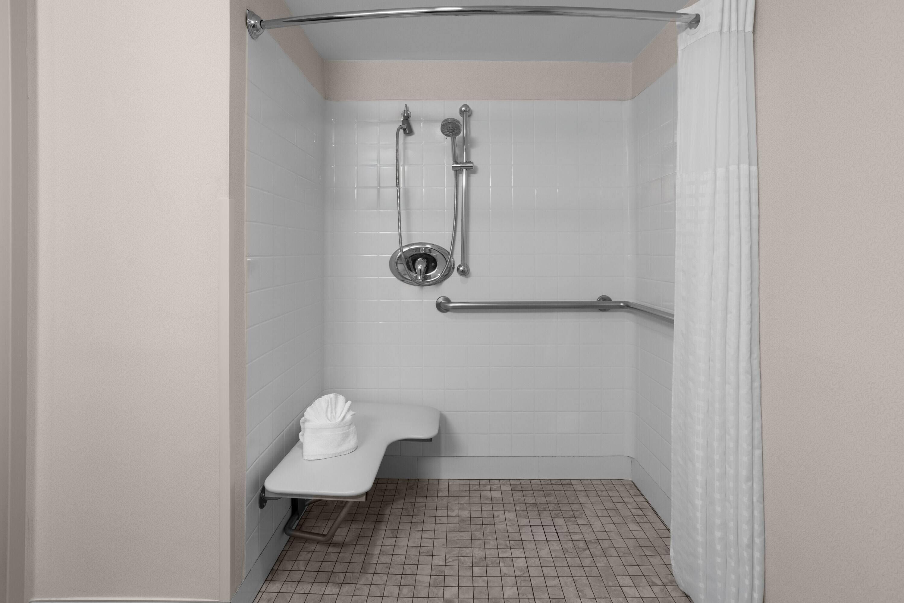 Une douche équipée d’une barre d’appui, d’un banc et d’un porte-serviettes.