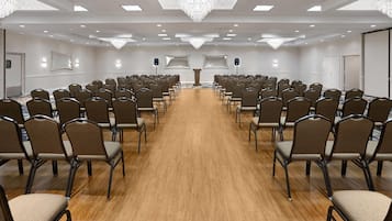 A conference room with rows of chairs, a podium, and a large chandelier.
