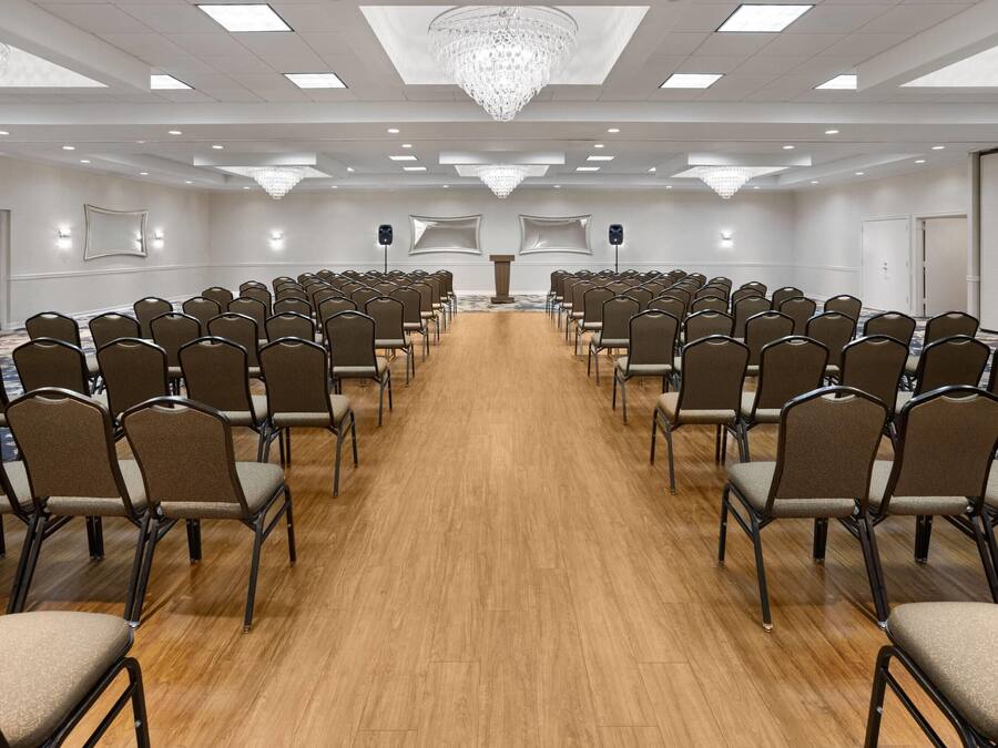 A conference room with rows of chairs, a podium, and a large chandelier.