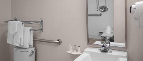 A bathroom with a toilet, a sink, a towel rack, a mirror, and a shower.